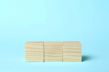 Wooden cubes on light blue background, space for text. Idea concept