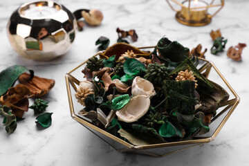 Aromatic potpourri of dried flowers in bowl on white marble table, closeup