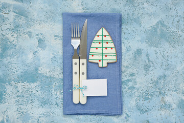 Napkin with cutlery and Christmas cookie on color background