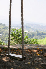 Beautiful wooden swing with ropes in mountain forest