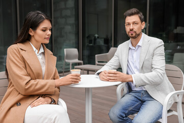 Upset arguing couple in outdoor cafe. Relationship problems