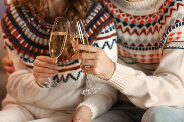 Young couple in love with glasses of champagne at home on Christmas eve, closeup