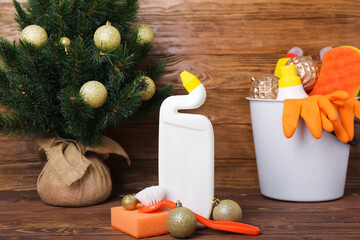 Cleaning supplies with Christmas tree and balls on wooden background