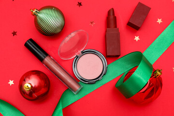 Makeup products with Christmas balls and ribbon on red background