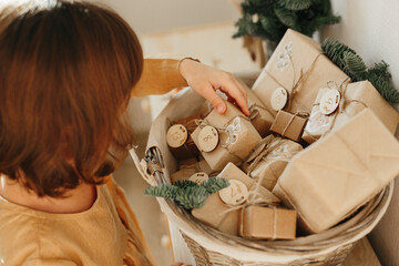 Christmas Advent calendar for kids. Girl wearing mustard linen dress looking at basket with advent...