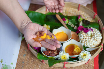 An elderly Asian woman receives a pain-relieving massage by a herbal therapist in a traditional Thai position.