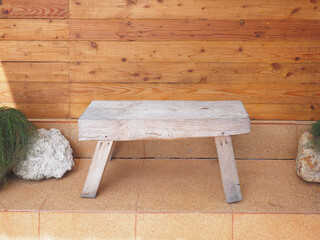 Bench made of old wood on pebble tiles over wooden plank background.