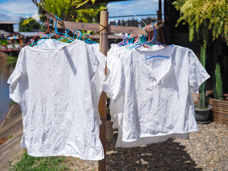 white shirt hanging by hanger on bamboo clothes line