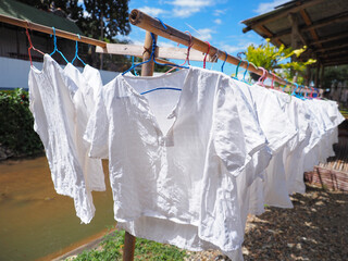 white shirt hanging by hanger on bamboo clothes line
