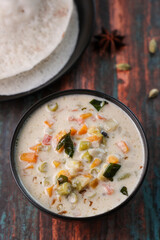 Mutton stew , veg stew soup side dish for Appam , bread, Kerala breakfast food. Indian food. Christian Christmas food woman hand take spicy curry with coconut milk, meat, vegetables, Indian spices