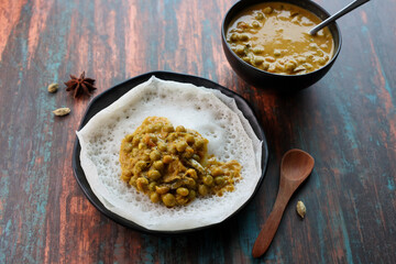Appam pancake Kerala breakfast food Kadala curry egg curry chickpea Masala and tea, Christian breakfast on wooden background. fermented rice pan cake. Top view of Indian veg food.