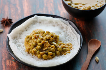 Appam pancake Kerala breakfast food Kadala curry egg curry chickpea Masala and tea, Christian breakfast on wooden background. fermented rice pan cake. Top view of Indian veg food.