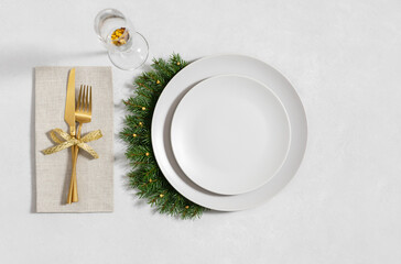 Christmas table setting with empty plate, golden cutlery and a glass on a gray background. Happy new year. Space for text. Winter concept. Top view, flat lay.