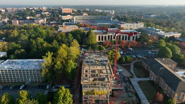 Large building construction project underway at college campus. Aerial orbit of crane at University of Georgia campus.