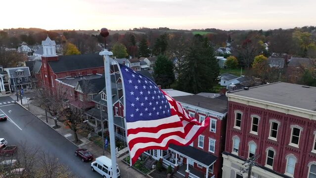 American flag waves in breeze. Slow motion aerial establishing shot of small town in USA. Patriotic Proud to be an American theme.