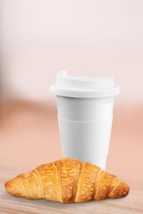 Coffee paper cup with fresh tasty croissant