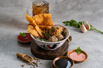Bakso or indonesian meatball served with broth soup, tofu, noodle and deep fried wonton or dumpling on white bowl