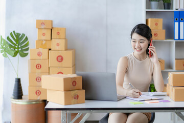 Young Asian woman working at home online selling on a box and laptop for SME business. Parcel delivery concept.