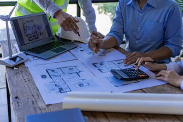 Architects and engineers point to buildings on blueprints and use laptops to draw house project...