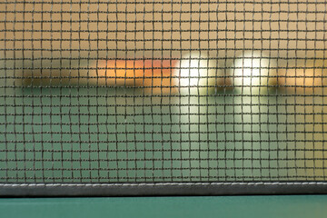 Table tennis attributes: racket, balls (background), table with a net (foreground).