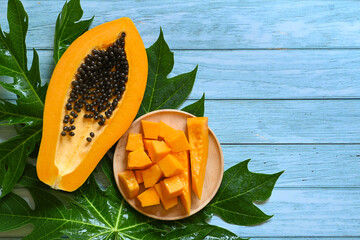 papaya fruits on blue backgroud, fresh ripe papaya slice cut in half tropical fruit with papaya seed and leaf leaves from papaya tree