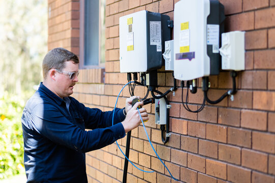 Electrician wiring wires while installing solar power on house