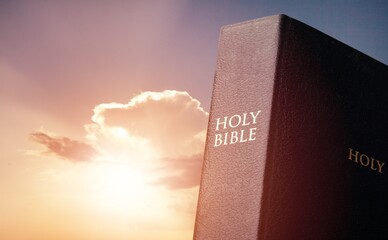 Praying concept. Holly bible book on sky background.