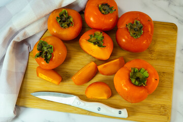 cook the persimmon with a knife. Sliced persimmon on a wooden table. Fresh ripe persimmons. Selective focus. 
