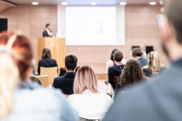 Speaker giving a talk in conference hall at business event. Rear view of unrecognizable people in audience at the conference hall. Business and entrepreneurship concept