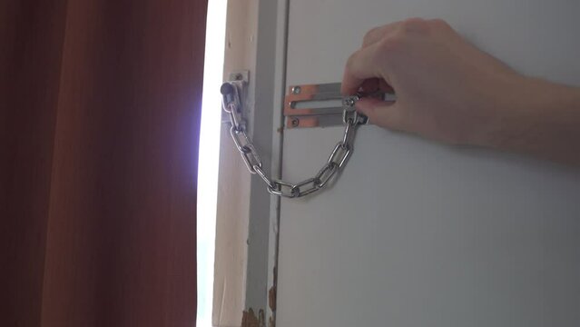 Man locks chain link lock on door in apartment/motel/hotel