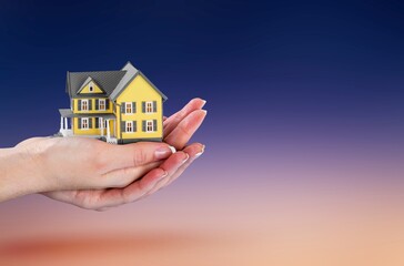 Person's hand with small model house