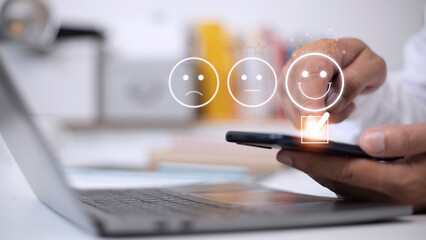 Customer service evaluation concept. using a smartphone is pressing face emoticon smiling in...