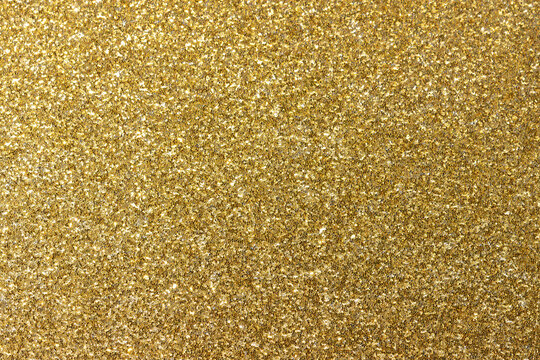Golden shiny background. New Year's bright yellow-gold abstract background for design. The concept of celebration, fun, glamour and luxury. Sparkling in the sun. Decoration of wrapping paper,fabric.