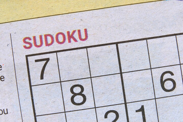 Daily Sudoku puzzle printed in newspapers for readers to use their brain power to try to solve the numbers and logic game. Sudoku number placement game to stimulate the brain. Closeup macro top view.