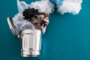 recycling and avoiding landfill, open trash can with single use plastic bags and paper flying into ot out of it