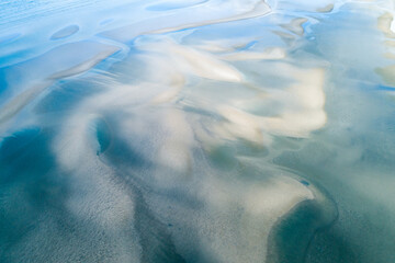 Aerial view of sandbar patterns in shallow blue water.