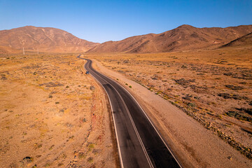 Fototapeta na wymiar carretera de asfalto en medio del desierto de atacama rodeado de montañas y paisajes áridos