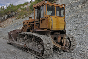 dirty bulldozer stands in the mud. Autumn construction site in a mountainous area with working machines.