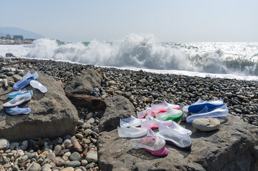 Plastic bathing shoes washed ashore by high sea waves. Close-up.