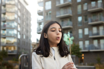 Girl blowing on pinwheel outdoors