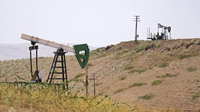 The oil pumps works in the mountains on a sunny day. Oil and gas production in progress