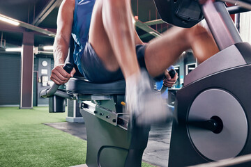 Fitness, cycling and training with man in gym for cardio, workout, health and exercise. Sports, endurance and wellness with shoes of athlete on bike machine for energy, power and strong mindset