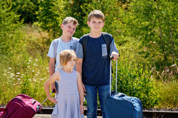 Three children, school boys and preschool girl with suitcases before leaving for summer vacation...