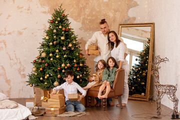 Obraz na płótnie Canvas Family - father, mother and three children, happy together at home celebrating Christmas at a decorated Christmas tree