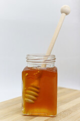 Sweet honey in a jar with a stick on a wooden board