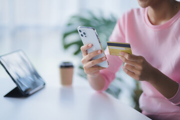 Closeup asian woman holding gold credit card and smartphone, sitting at home, happy satisfied young female customer shopping online, purchasing, making secure online payment.