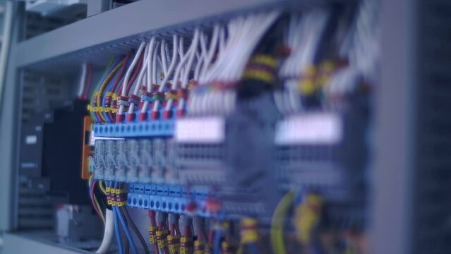 Electrical box with many wires, rows of switches, electrical parts, automatic breakers. Closeup. Follow focus