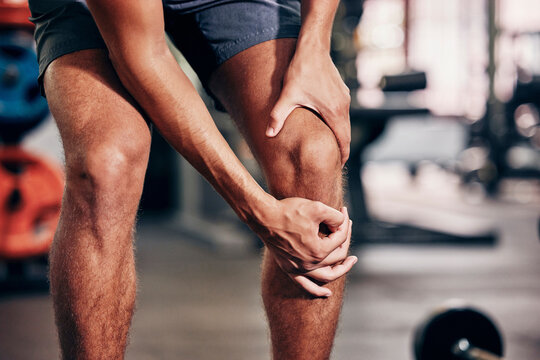 Fitness, exercise and man with knee pain in gym holding leg after injury, accident and muscle pain. Healthcare, sports and male athlete with sore joint, hurt after exercising, workout and training
