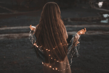 Portrait of girl with light LED garland outdoor holds a  lightes. Fairy illumination winter christmas mood. Selected focus