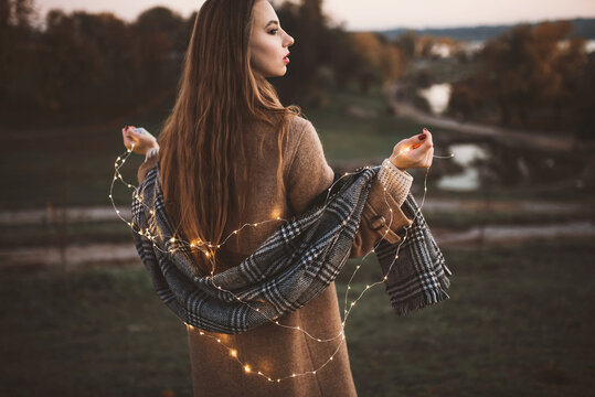 Portrait of girl with light LED garland outdoor holds a  lightes. Fairy illumination winter christmas mood. Selected focus